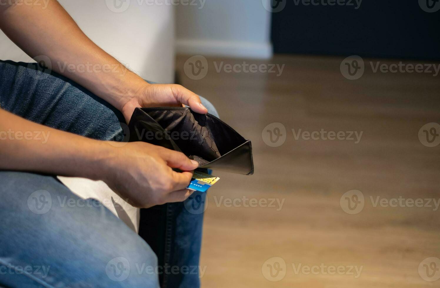 Man sitting on bed and opening his wallet with no money in it, luxury spending, poverty, lifestyle concept and saving for future photo