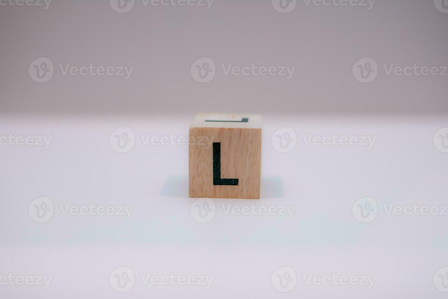 Wooden block written L with a white background, education concept, close up. photo