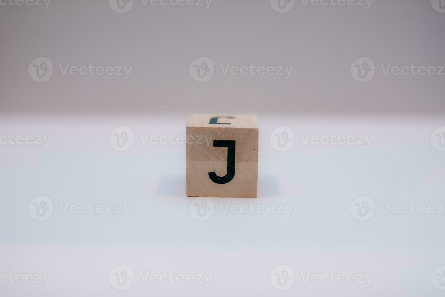 Wooden block written J with a white background, education concept, close up. photo