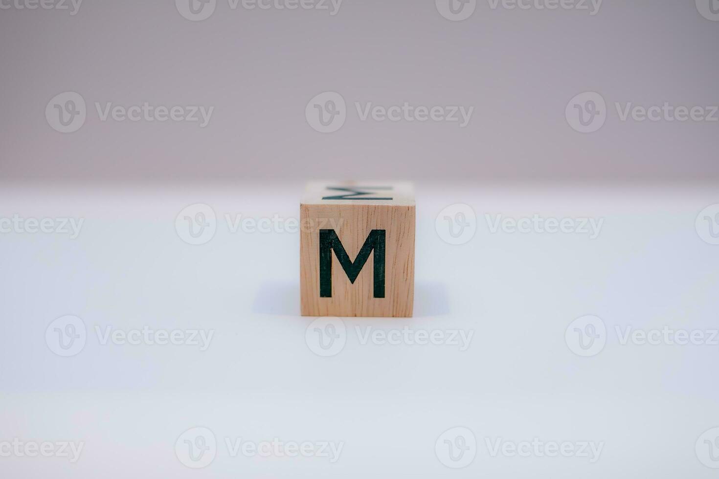 Wooden block written M with a white background, education concept, close up. photo