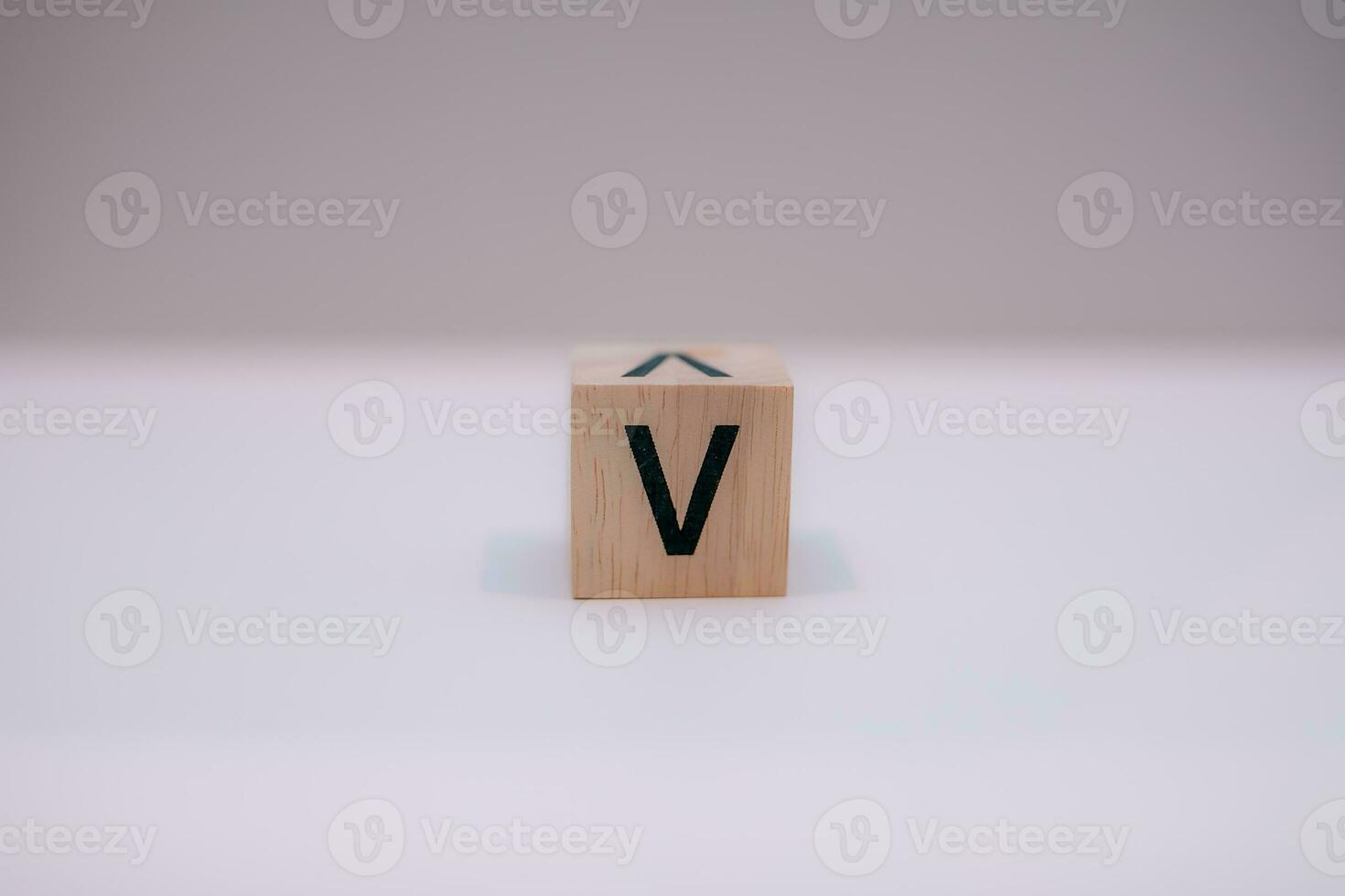 Wooden block written V with a white background, education concept, close up. photo