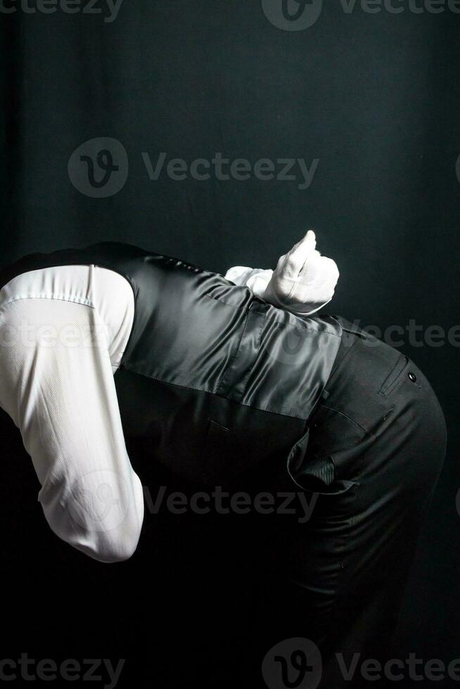 Portrait of Butler or Concierge in Vest and White Gloves Bowing in Courteous Greeting. Concept of Professional Hospitality. photo