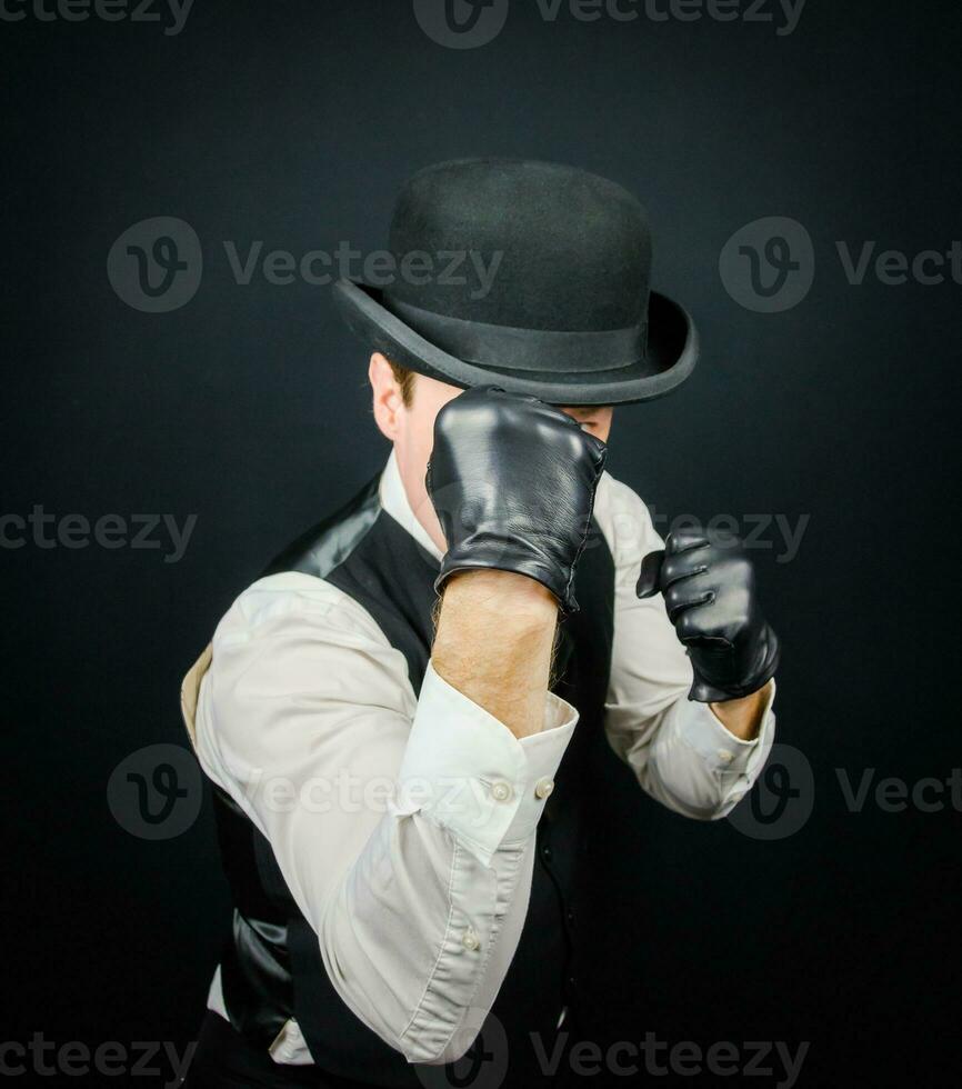 Portrait of Dangerous Vintage Fighter in Vest and Bowler Hat Standing in Karate Stance. Mobster in Black Leather Gloves. photo