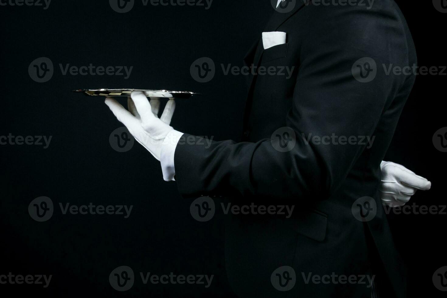 Portrait of Elegant Butler or Concierge in Dark Suit and White Gloves Holding Silver Serving Tray. photo