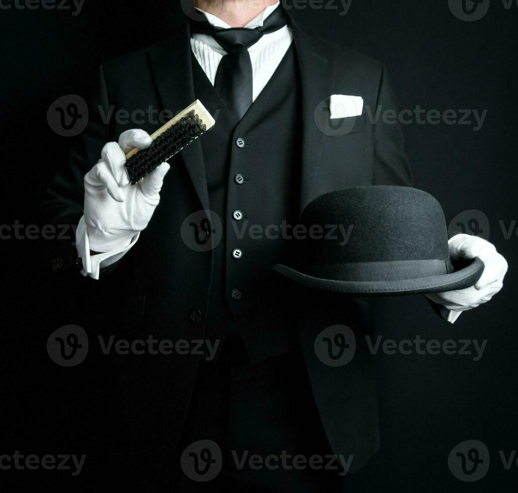 retrato de mayordomo en oscuro formal traje y blanco guantes cepillado un jugador de bolos sombrero. concepto de Servicio industria y profesional hospitalidad. foto