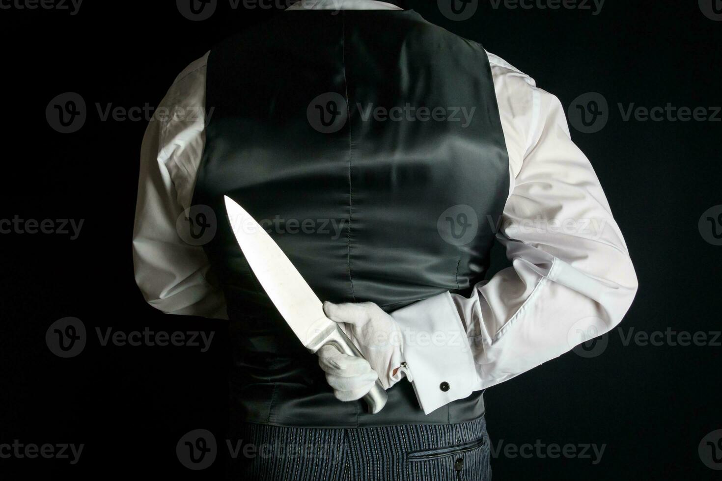 mayordomo o camarero en negro chaleco o chaleco participación agudo cuchillo detrás su atrás. concepto de mayordomo hizo él. clásico asesinato misterio. foto