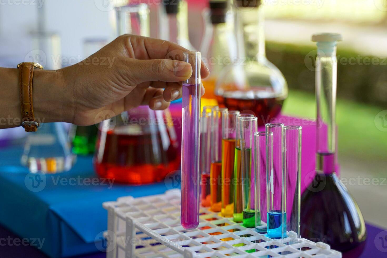 Hand holding a test tube with solution to observe and compare with results from other tubes. Then analyze and summarize the experimental results. Soft and selective focus. photo