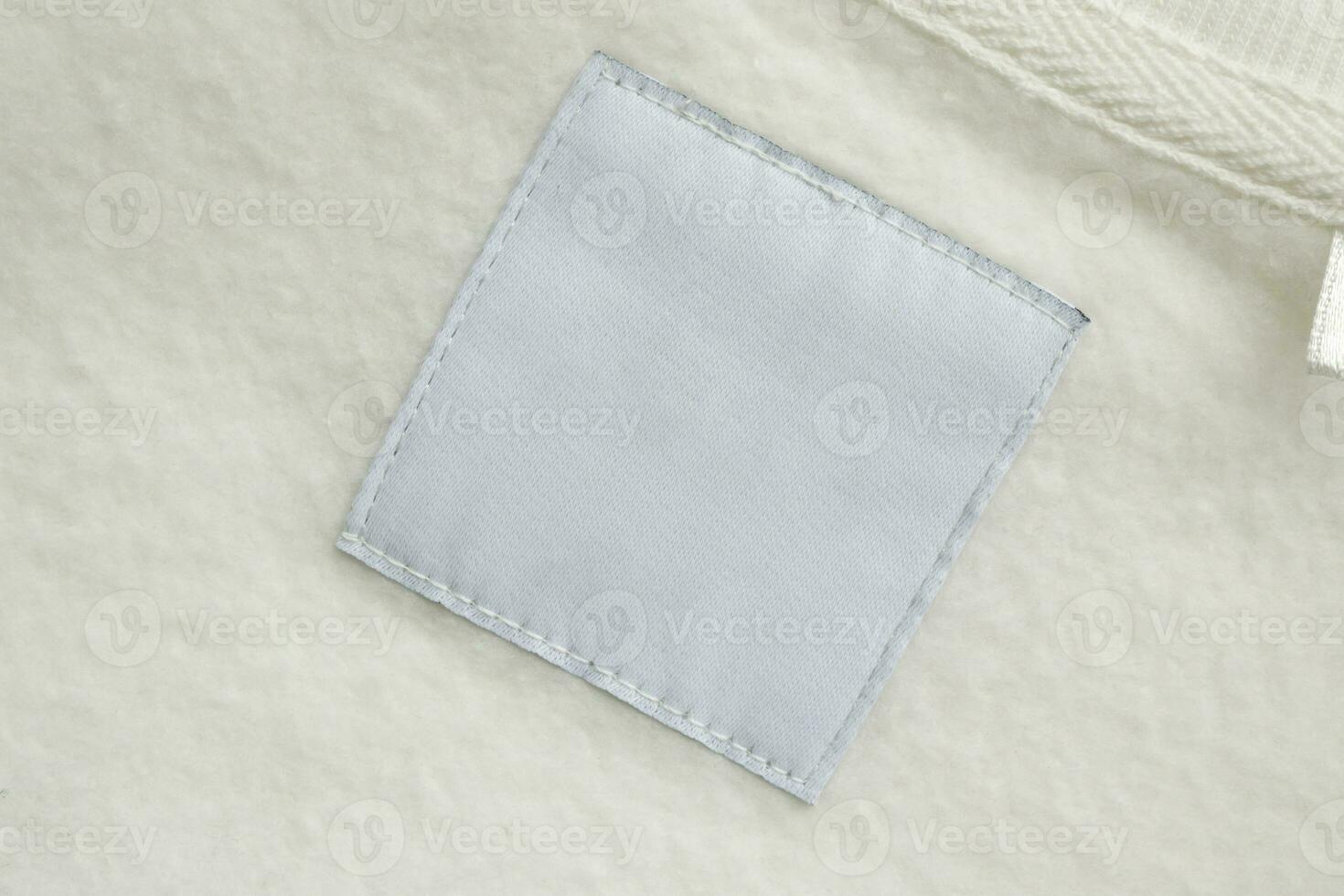 Blank white laundry care clothes label on fabric texture background photo