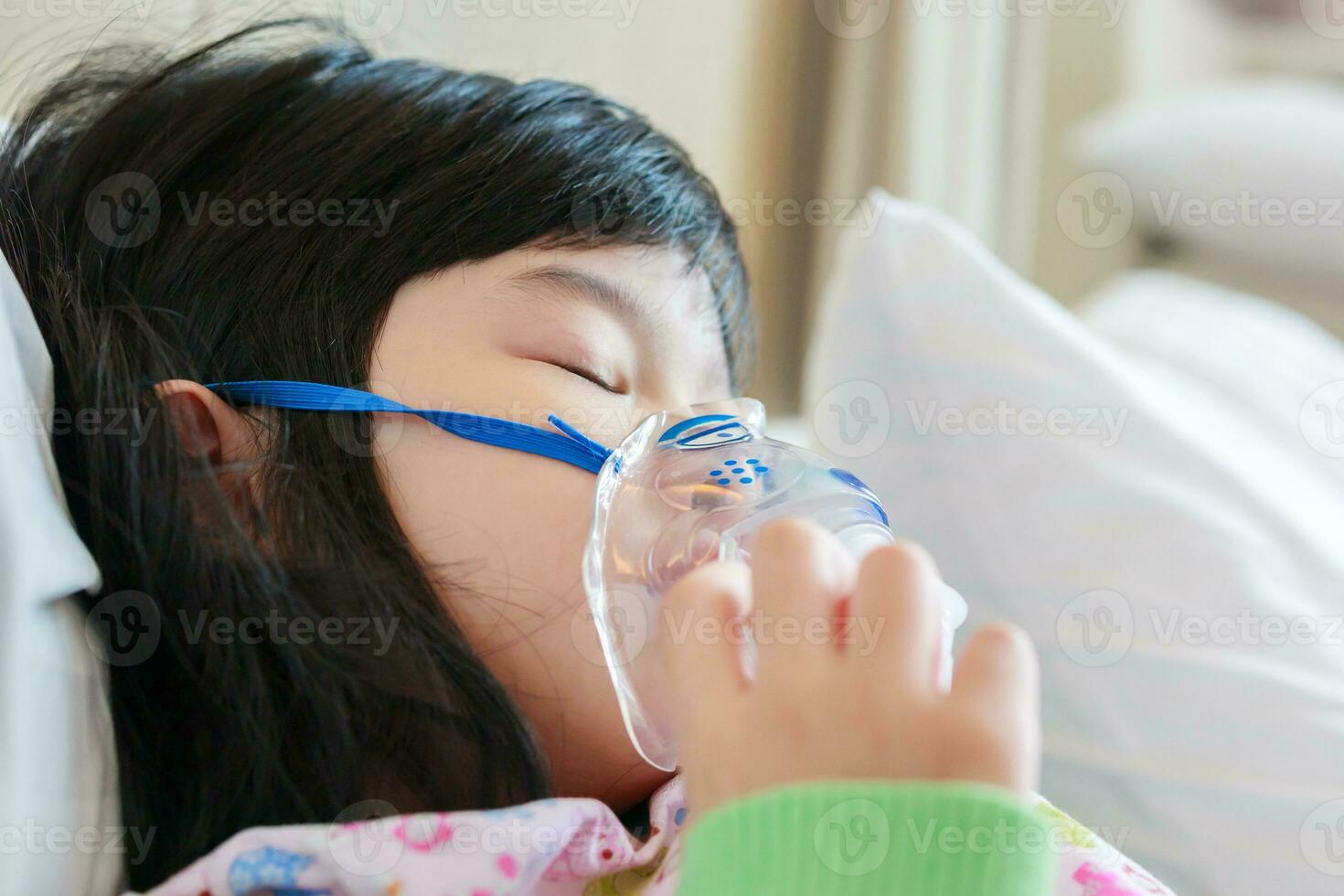 Sick little asian girl inhalation with nebulizer for respiratory treatment photo