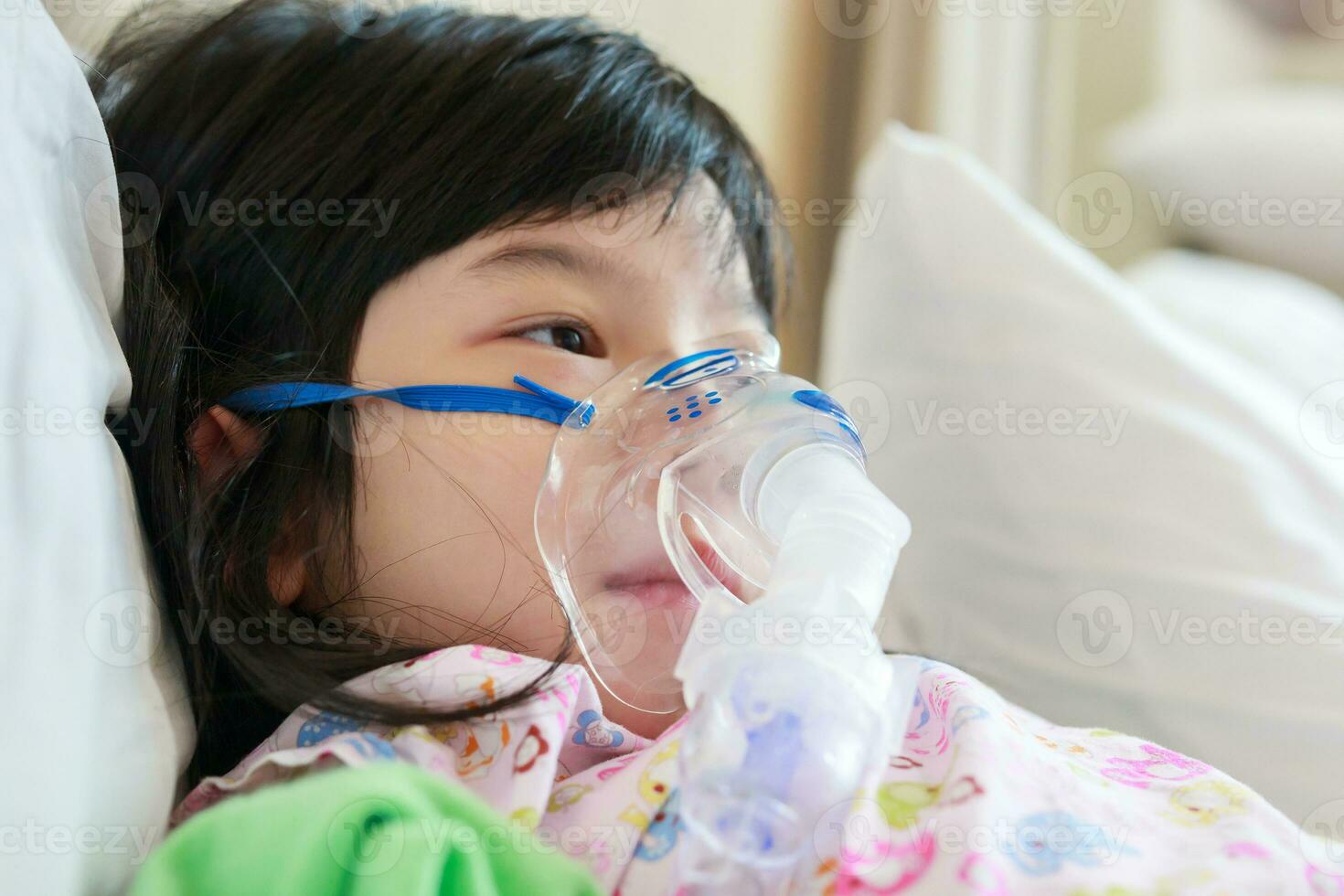 Sick little asian girl inhalation with nebulizer for respiratory treatment photo