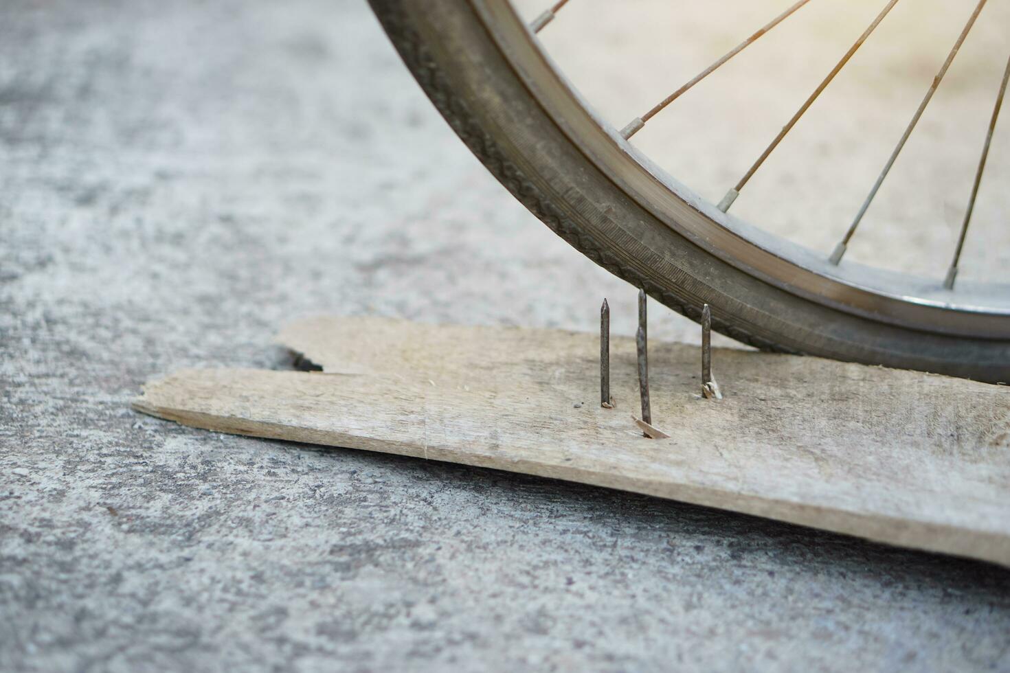 cerca arriba uñas en madera tablero y plano bicicleta neumático. concepto, inseguro , daño. ser Cuidado y Mira alrededor durante ciclismo en el piso o riesgo lugares. accidente lata ser sucedió. foto