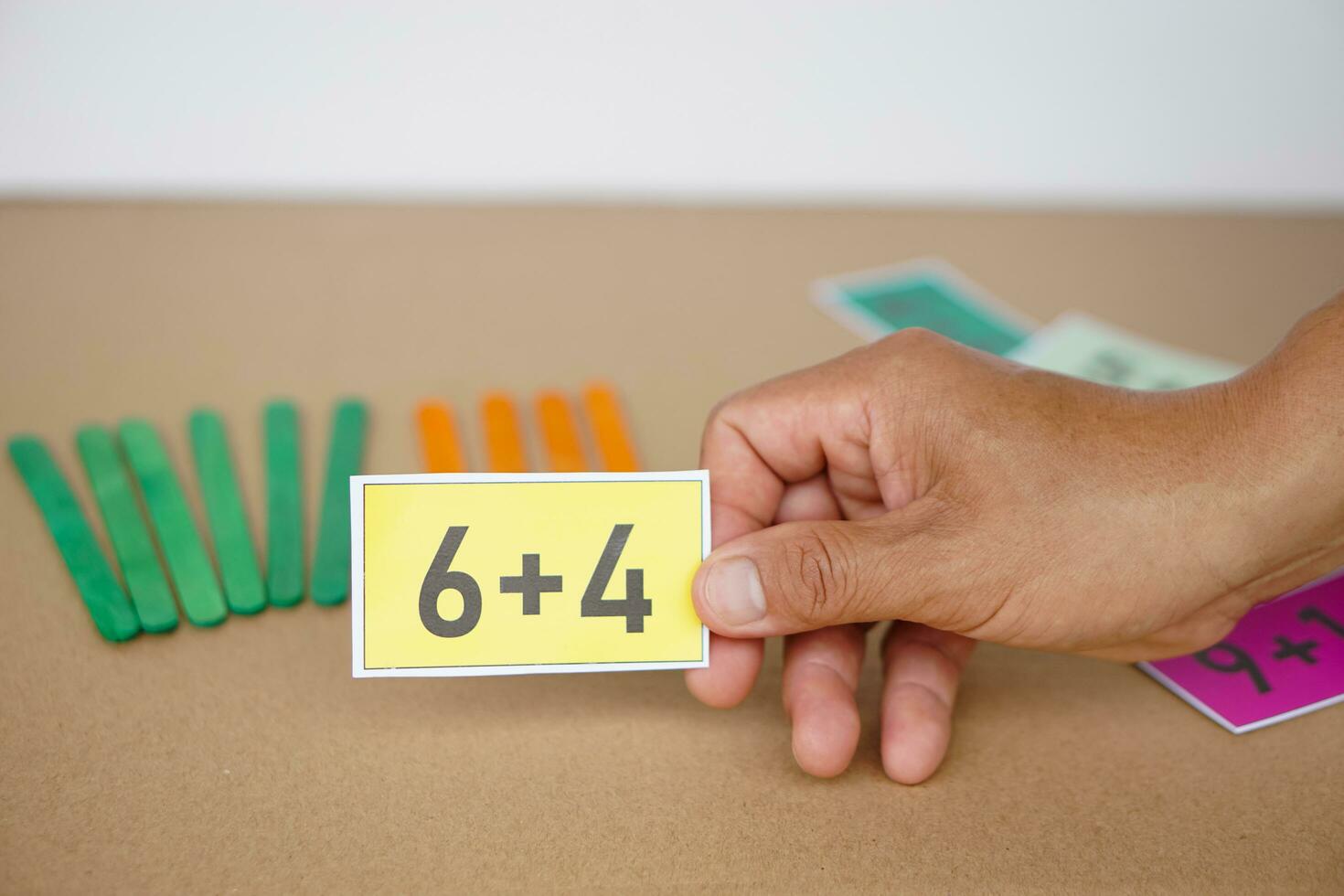 Close up teacher hand hold yellow card with number 6 plus 4  for teaching Math subject. Concept, Education, Teaching aid, materials for preschool kids. Education, Calculation lesson. photo