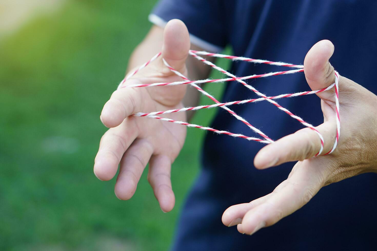 Closeup man hands is playing rope which called cats cradle game