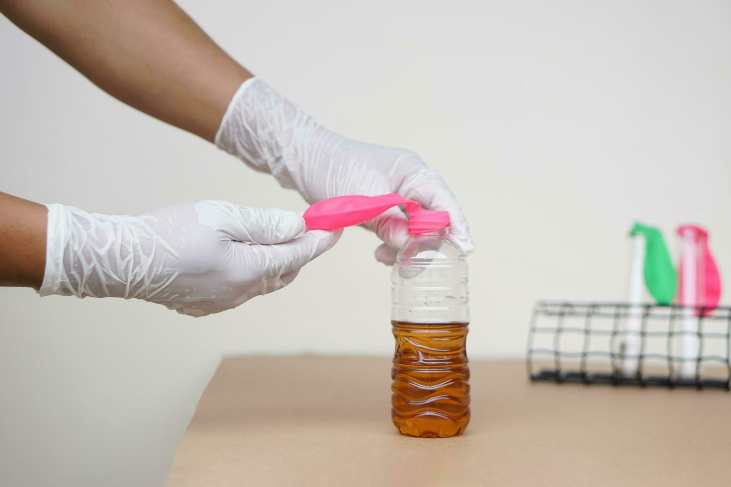 Hand holds pink  balloons on top of transparent test bottles with soft drink mix baking soda. Concept, science experiment about reaction of chemical substance. photo