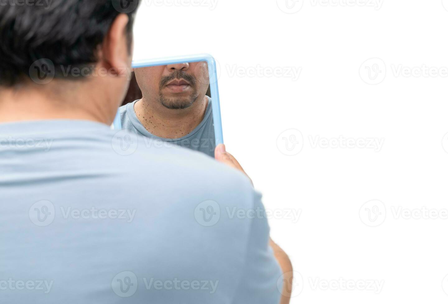 Bearded man looking in the mirror for skin tags or acrochordon on his neck photo