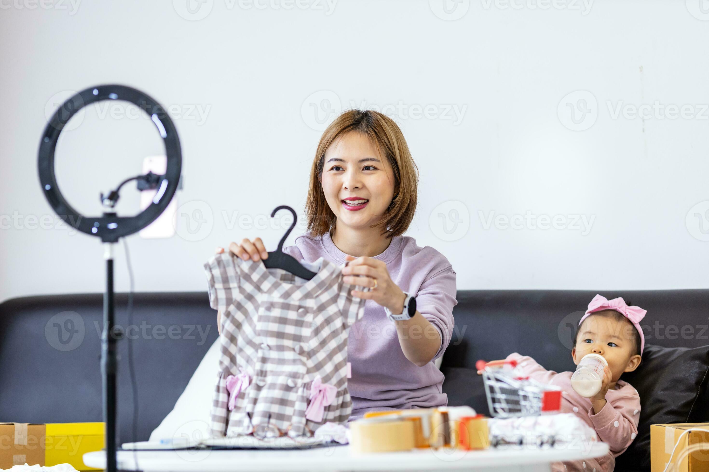 Young Asian influencer mother is selling children clothes live online