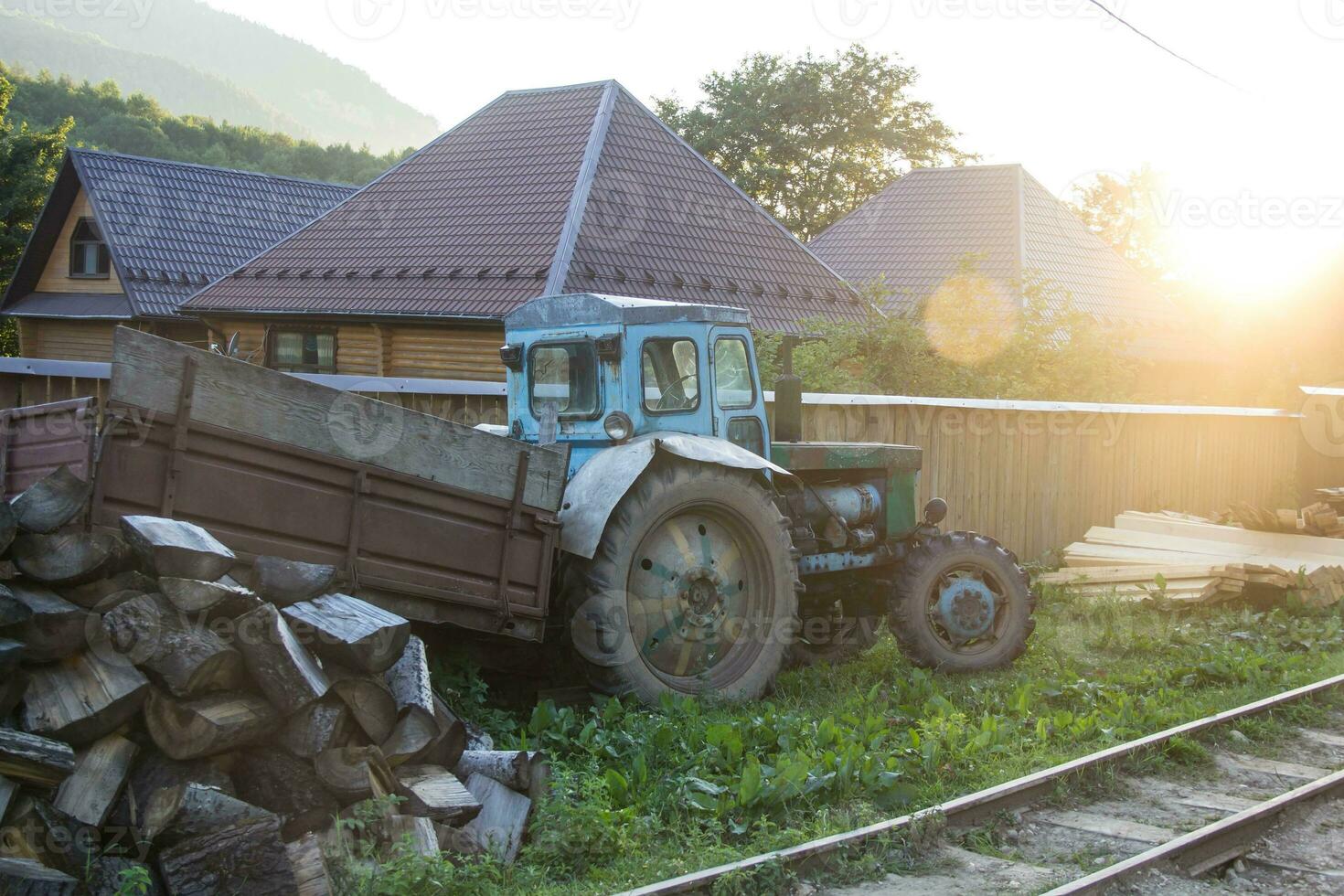 Russian old tractor in the village in the mountains with summer sunset photo