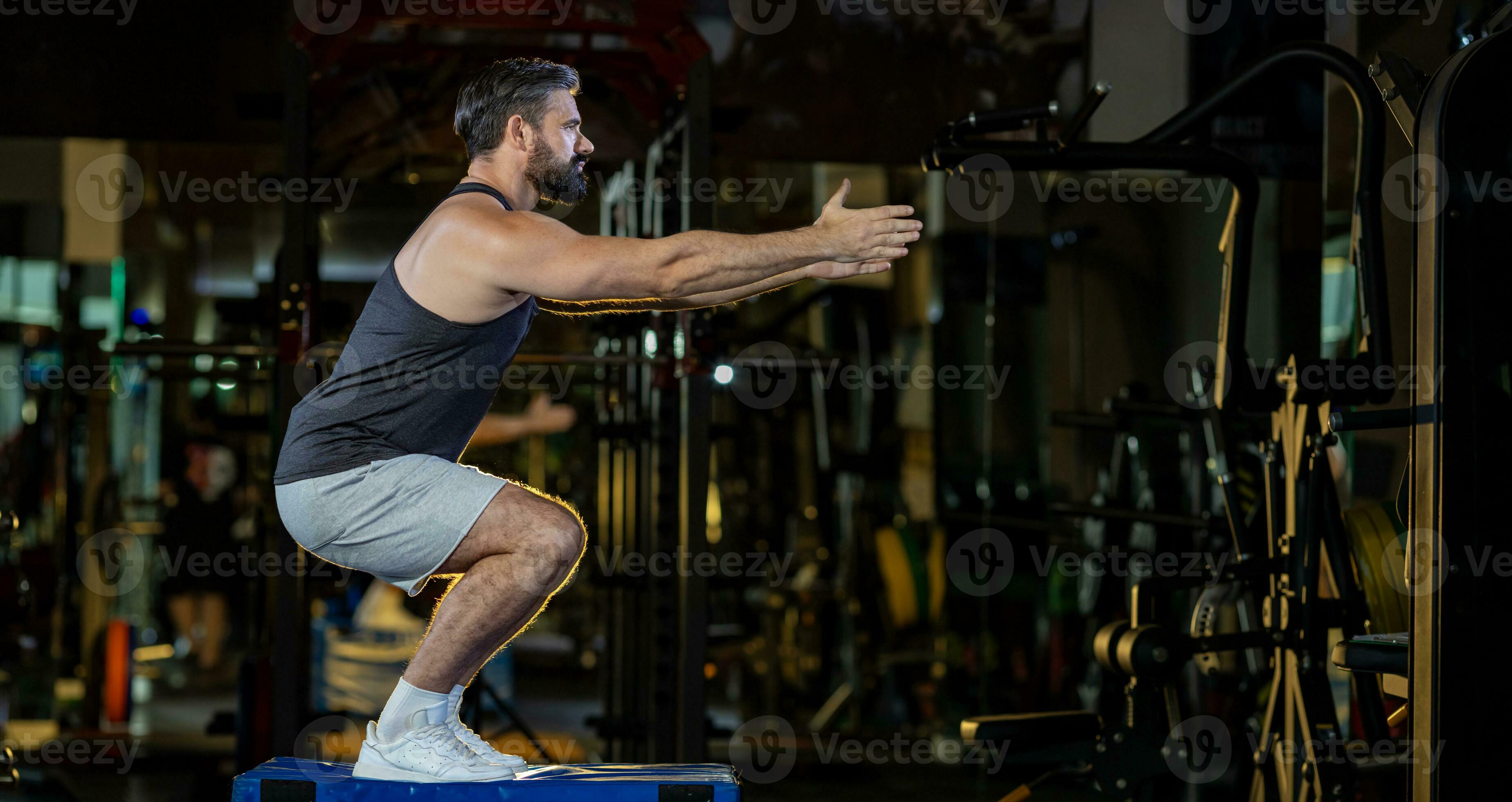 Caucasian man with strong and muscular firm shape is training on leg day by  doing advance jump squat for thigh and calf muscle in gym for healthy and  strong lower body weight