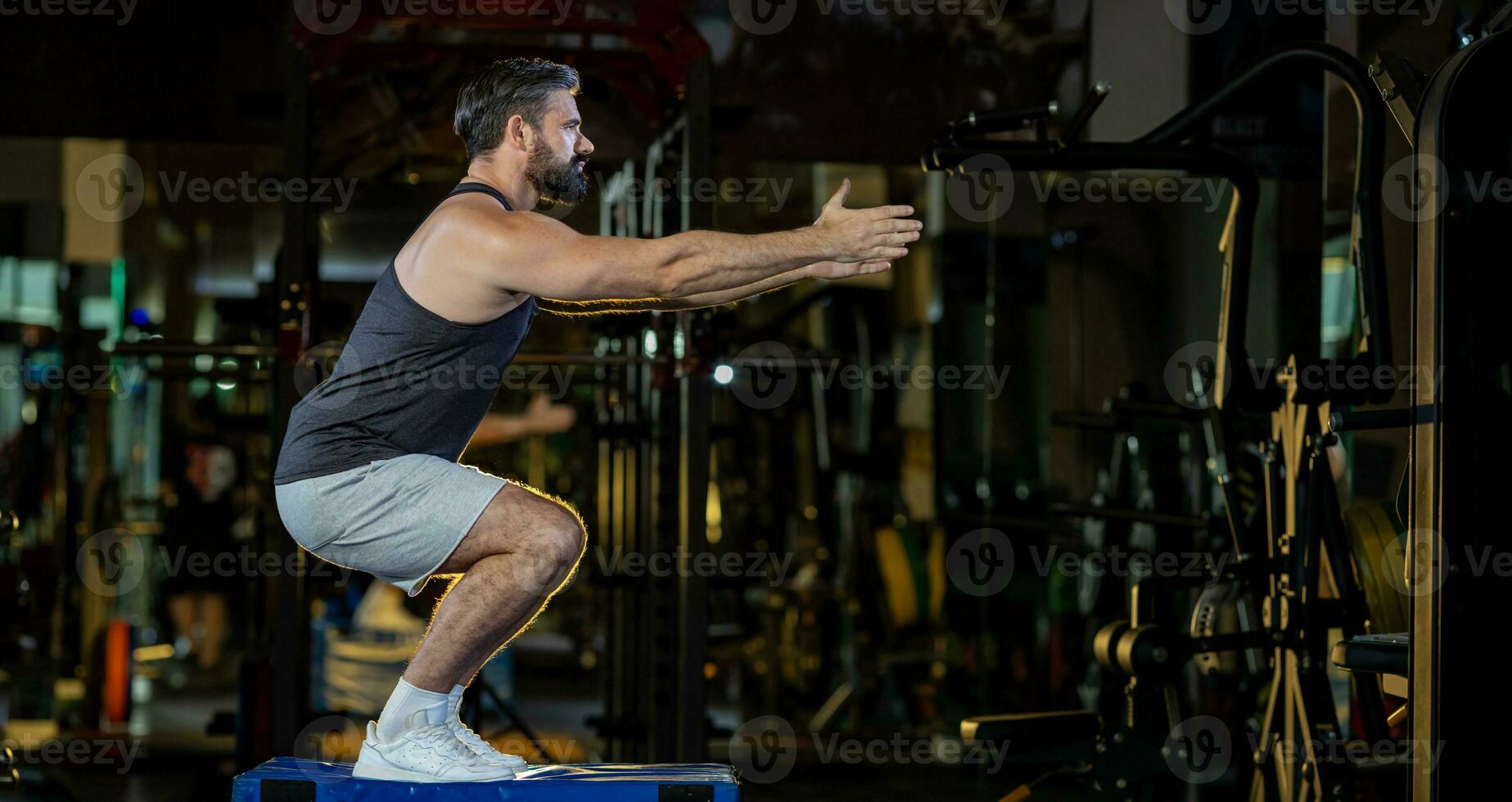 Caucasian man with strong and muscular firm shape is training on leg day by doing advance jump squat for thigh and calf muscle in gym for healthy and strong lower body weight strength with copy space photo