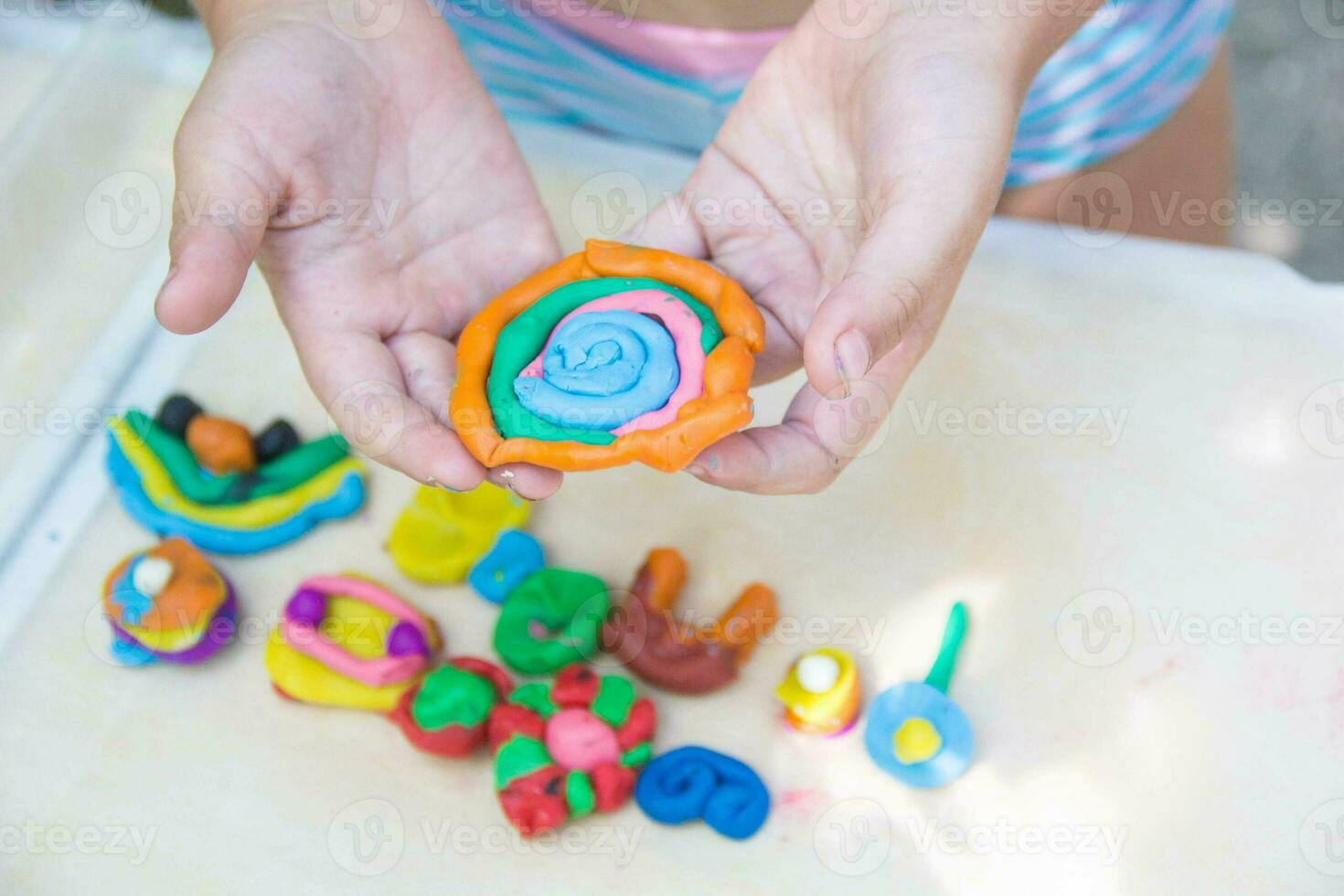 Child playing with colorful clay making animal figures. closeup on hands photo