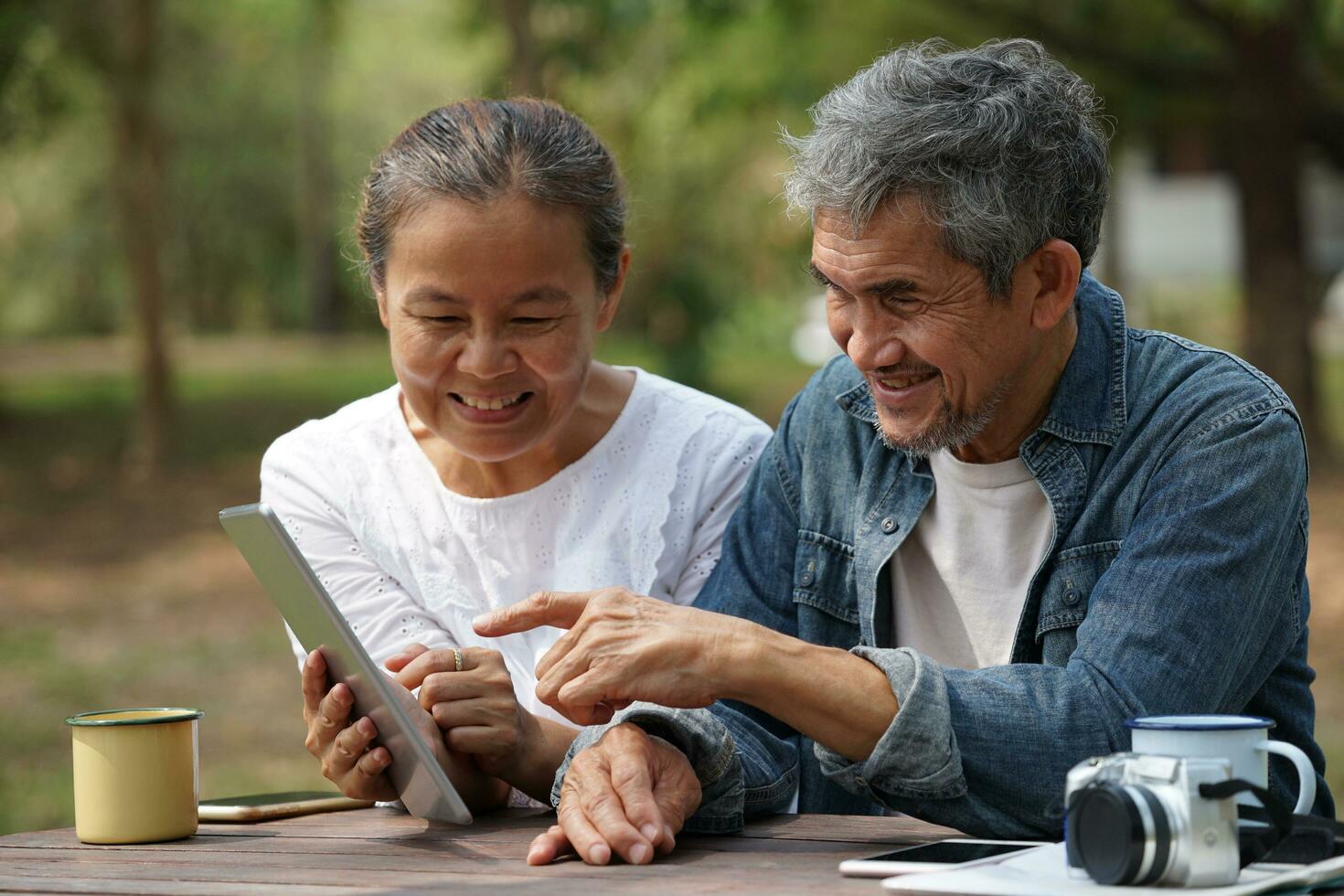 happy senior couple sitting together and looking at camera,old tourist people relaxing at resort garden in the countryside,concept of elderly pensioner travelling photo
