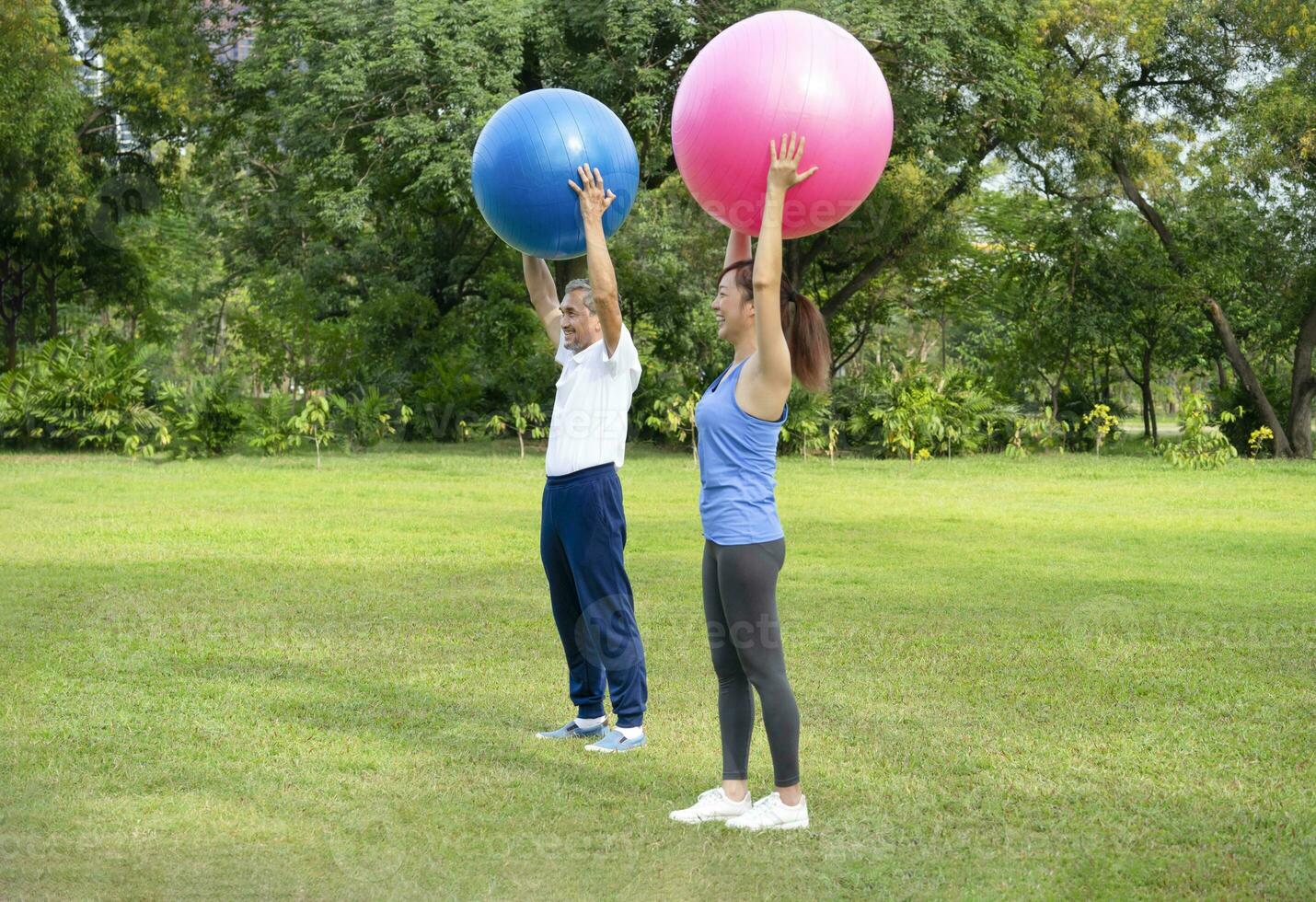 senior man and his daughter is enjoy doing exercise with gym ball in green nature, concept for elderly people activity, family relationship photo