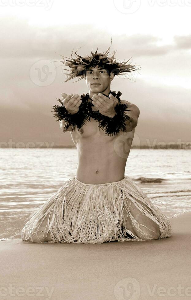 This is not AI generated - In a classic hula pose, a man hula dancer kneels on the wet beach beside the ocean. photo