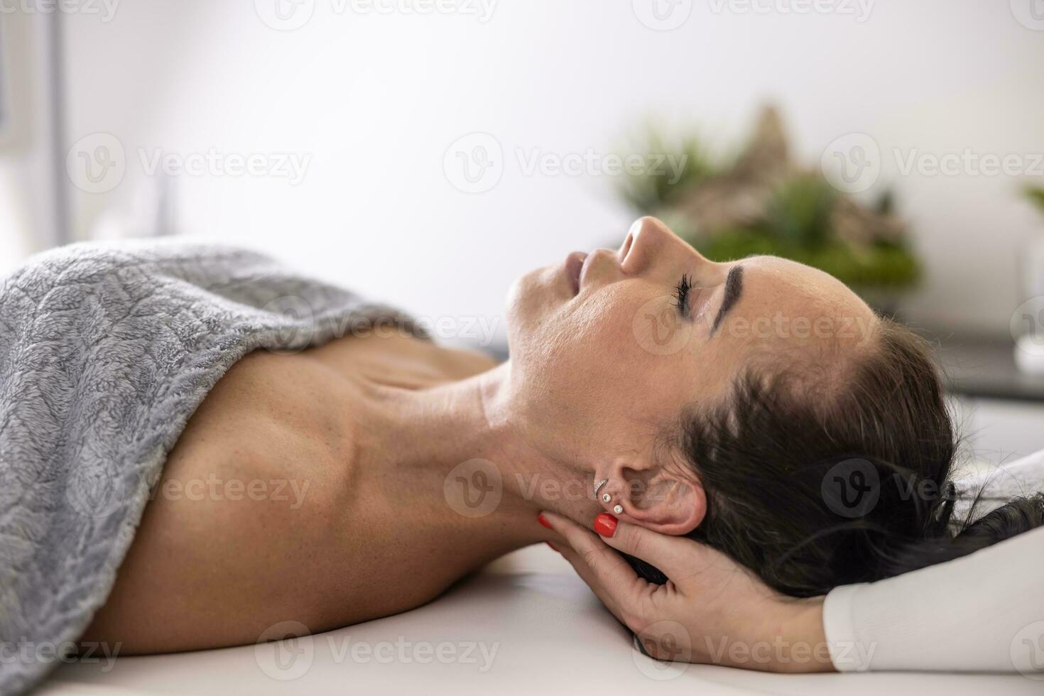 Masseuse finishes her massage with gentle touches easing tension from moscles at the back of her client's head photo