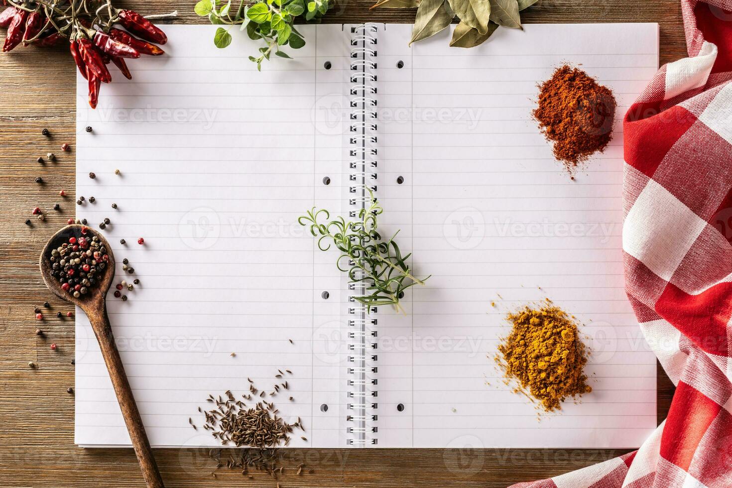 Open notebook with spices and herbs, chili, oregano, curry, basil, cummin ,bay leaf, and rosemary photo
