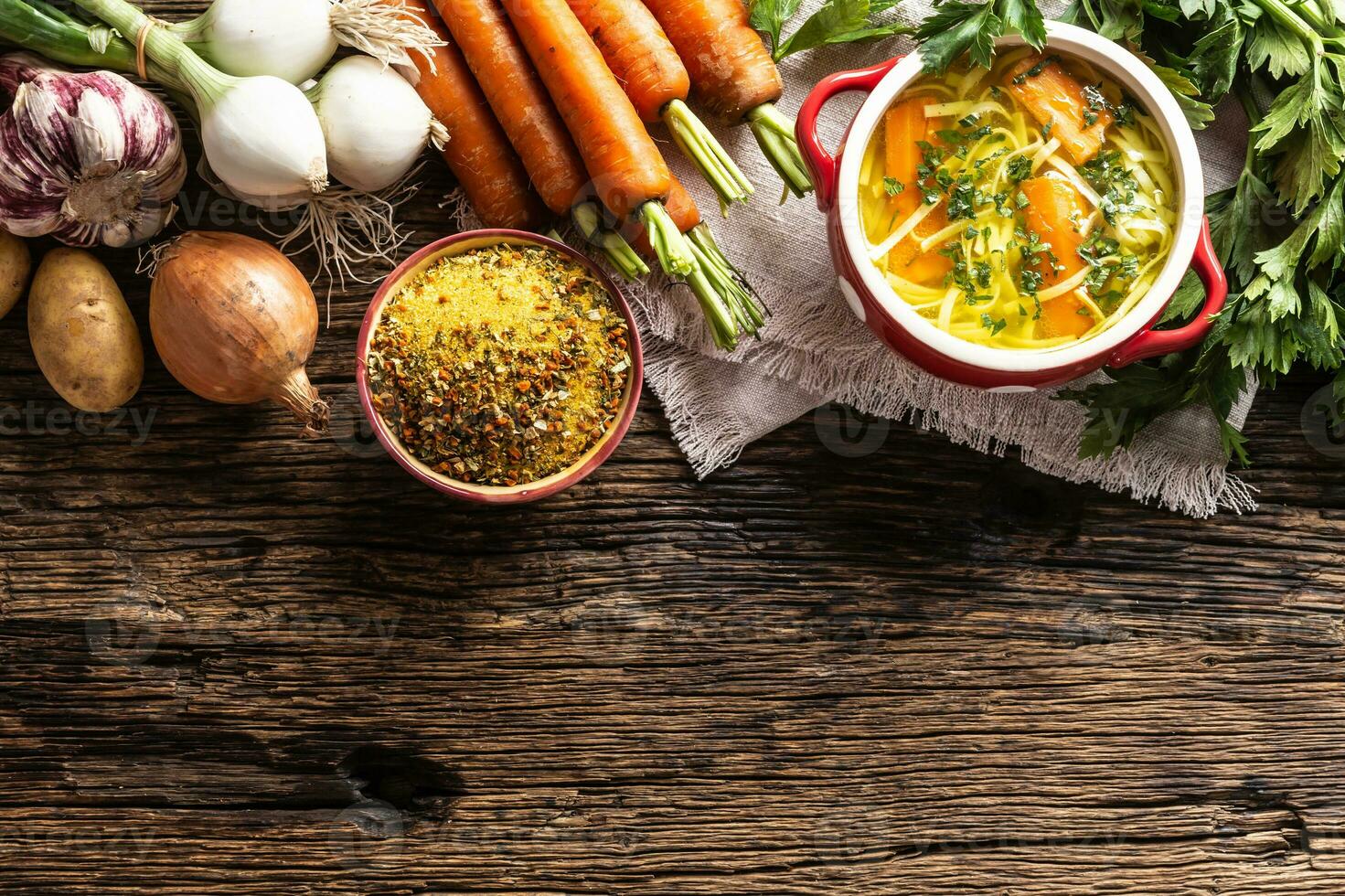 Chicken soup broth in a vintage bowl with homemade noodles carrot onion celery herbs garlic and fresh vegetables. photo