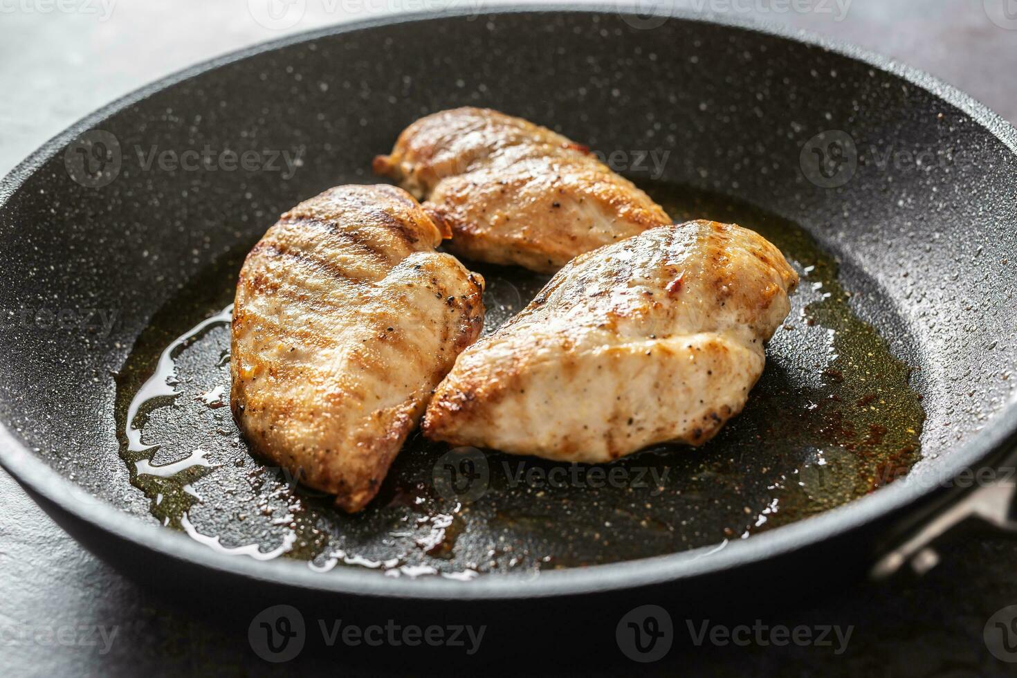 Pan-fried juicy chicken breasts on a dark pan photo