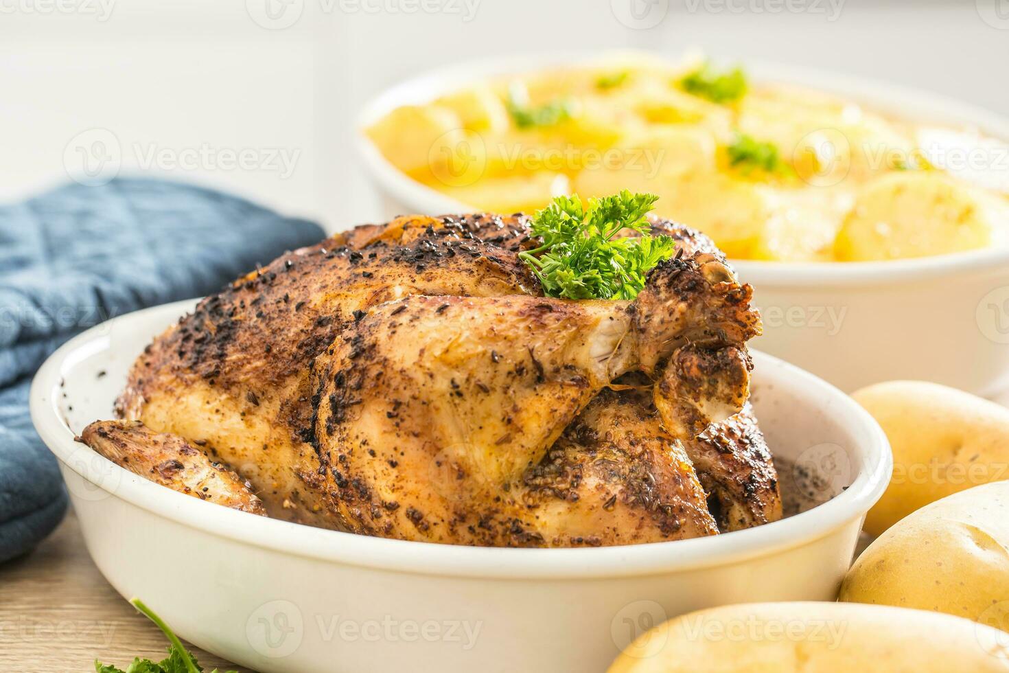 Whole chicken roasted in a porcelain bowl with potatoes photo