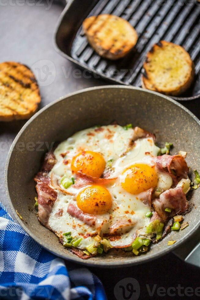 English breakfast fried bacon ham and eggs in ceramic pan photo