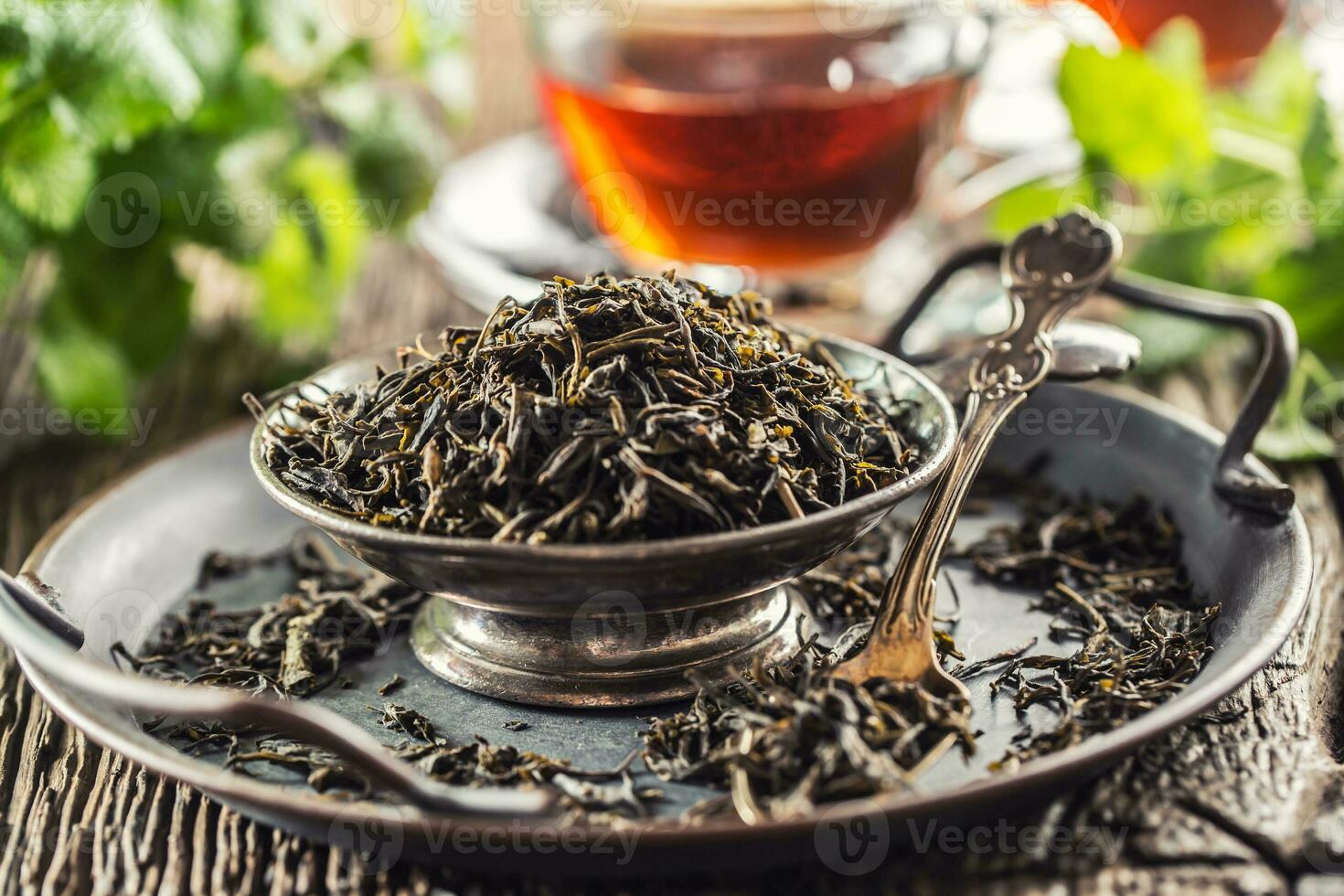 Dried tea leaves in bowl on rustic wooden table photo