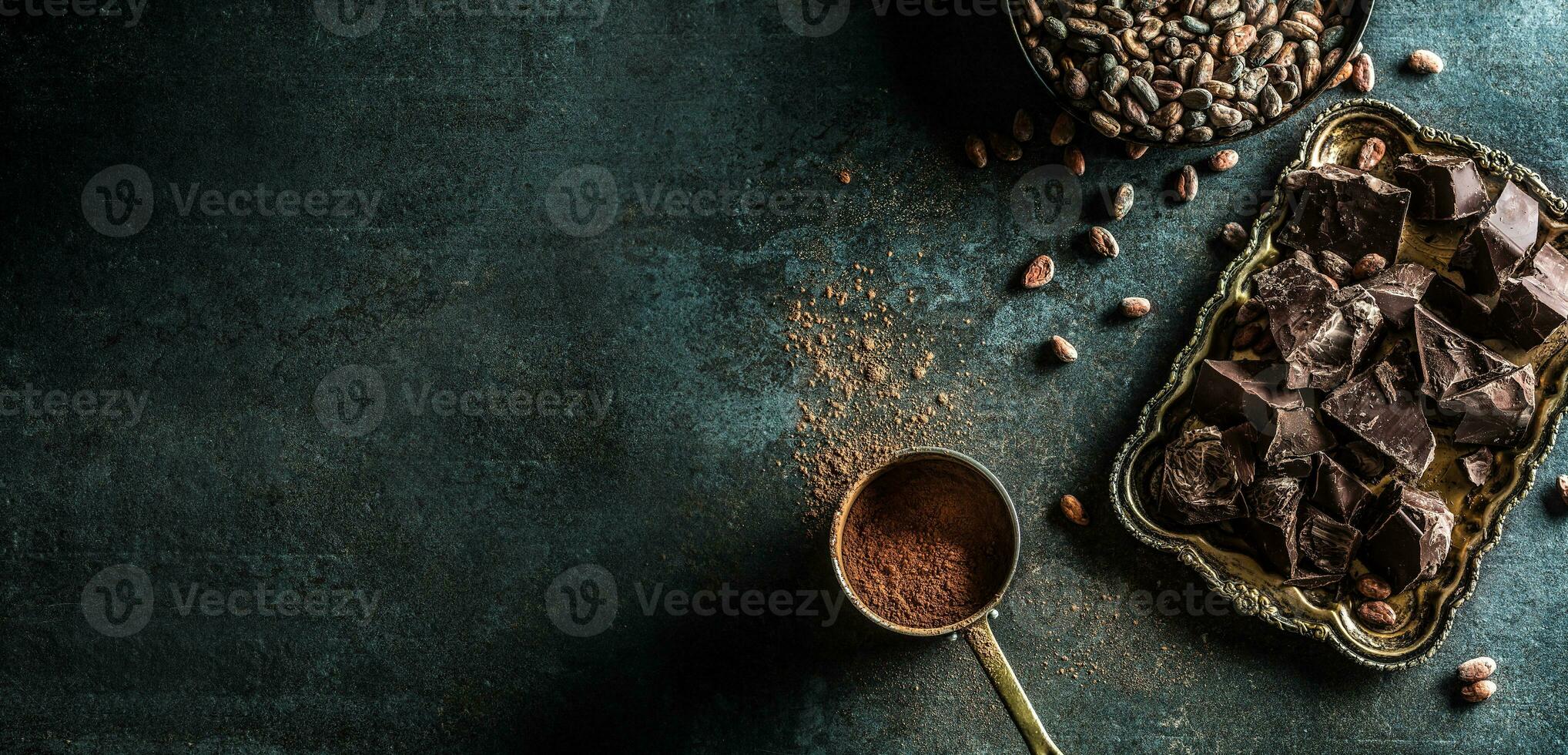 Dark chokolate cocoa beans and powder on concrete table photo