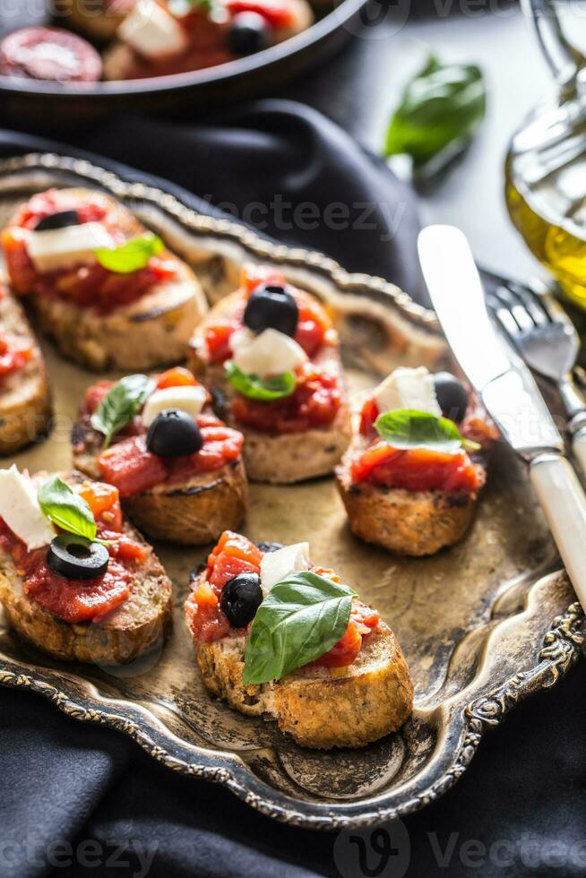 Bruschetta toast with mozzarella tomatoes olives and basil. photo