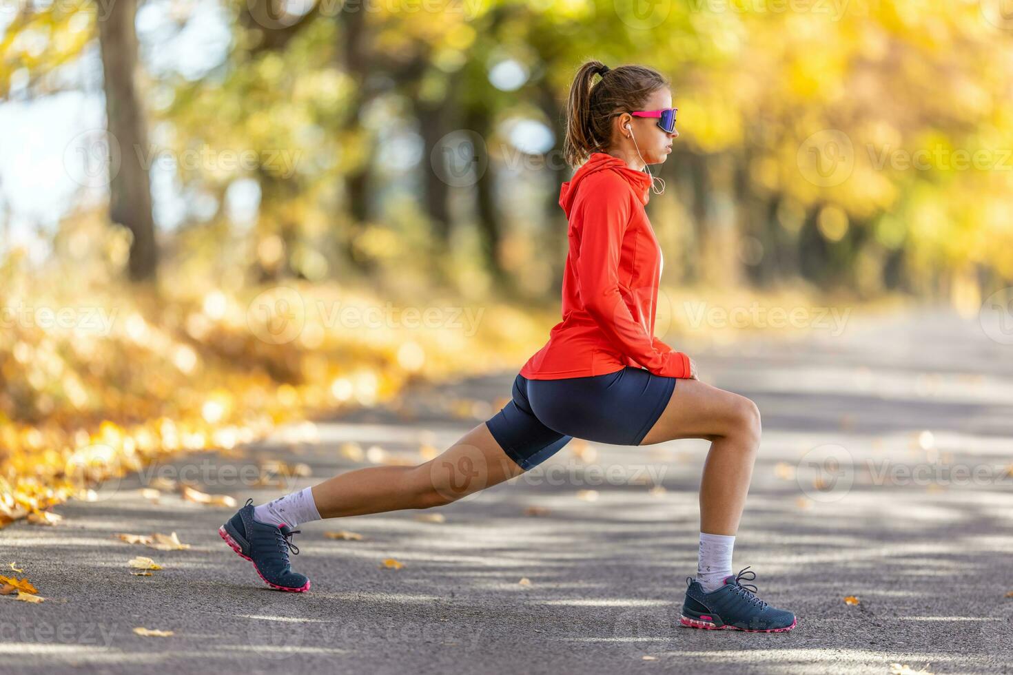 joven hembra atleta en ropa de deporte es calentamiento arriba antes de corriendo en el otoño parque foto