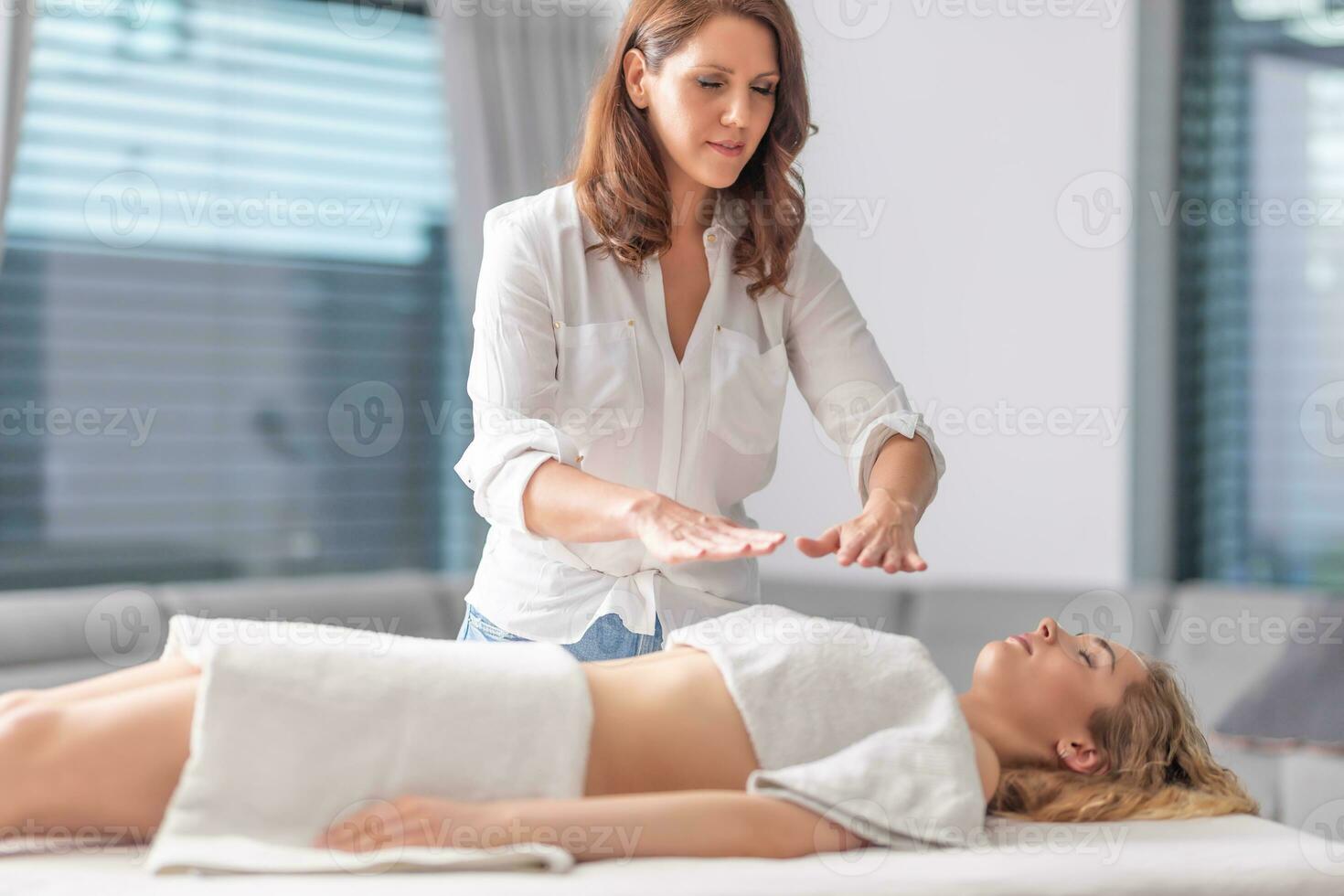 enfocado reiki curador haciendo terapia sesión con un joven hermosa mujer en salud spa centrar foto