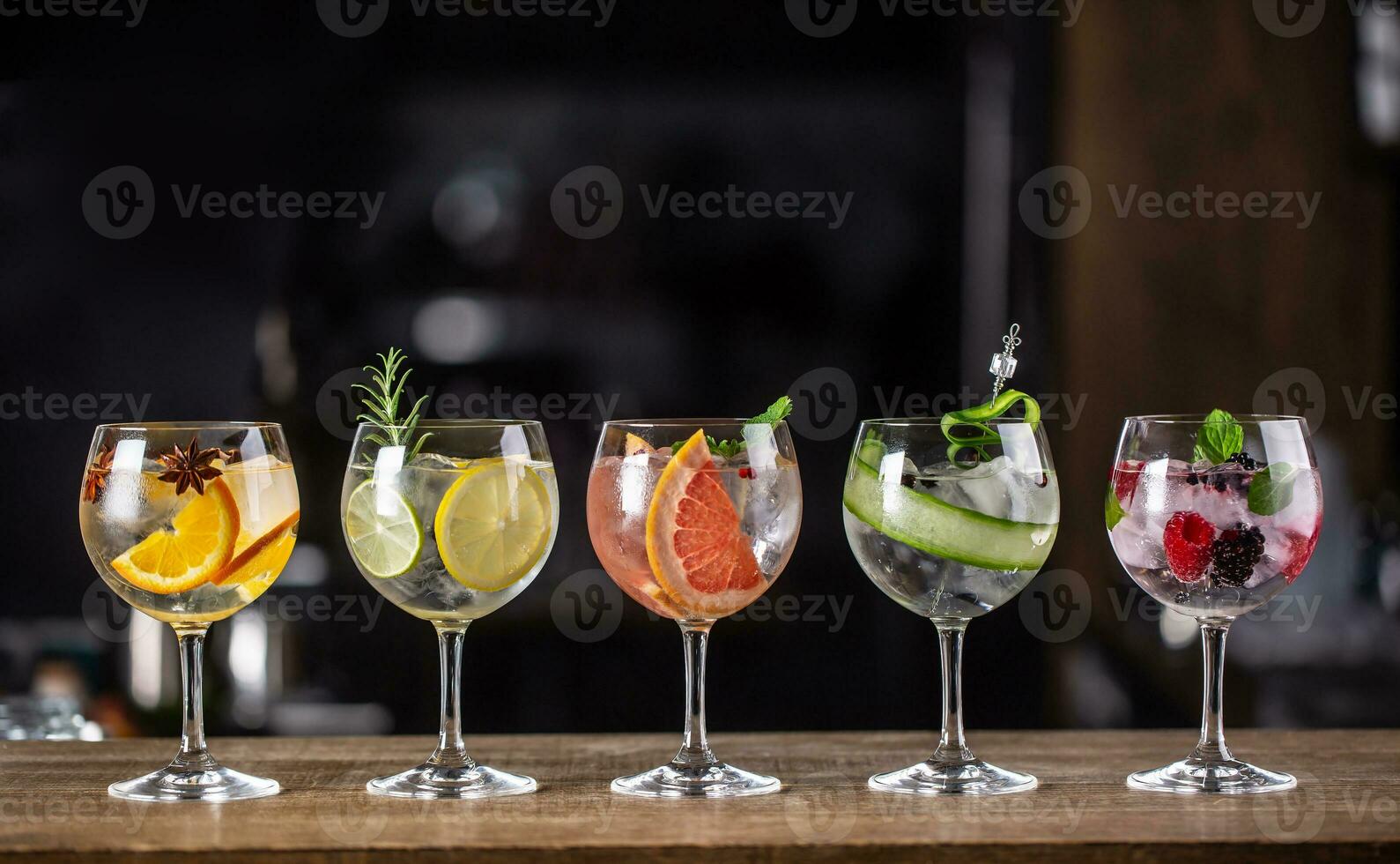 Ginebra tónico largo bebida como un clásico cóctel en varios formas con adornar en individual lentes tal como naranja, limón, pomelo, Pepino o bayas foto