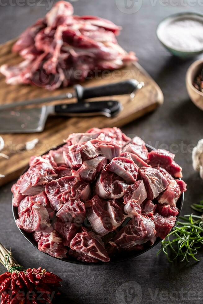 Small beef cuts in a bowl ready for making a soup or a stew with cutting board and knives in the background photo
