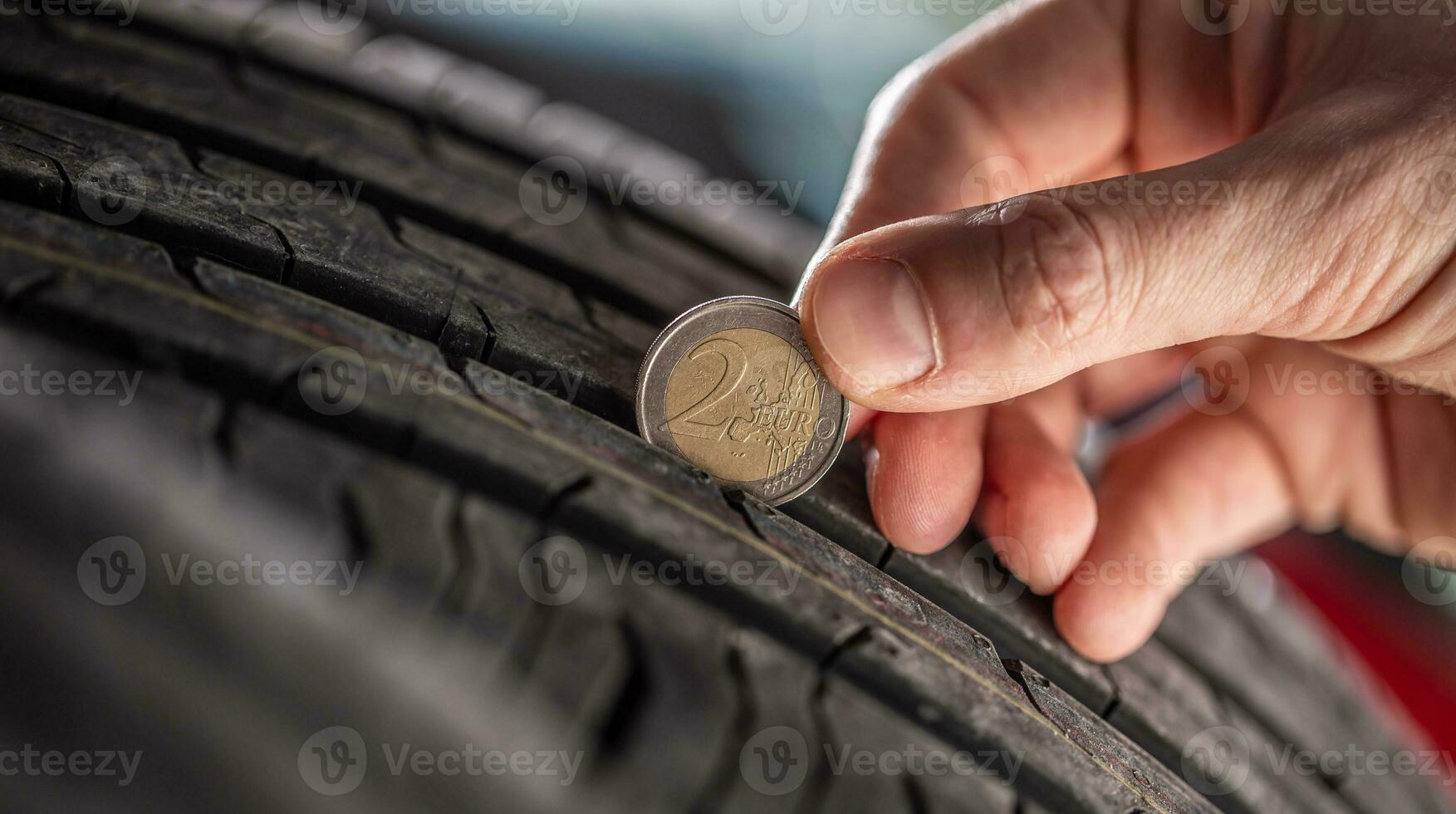 Tire tread measuring by a two euro coin placed into the pattern of the tire photo