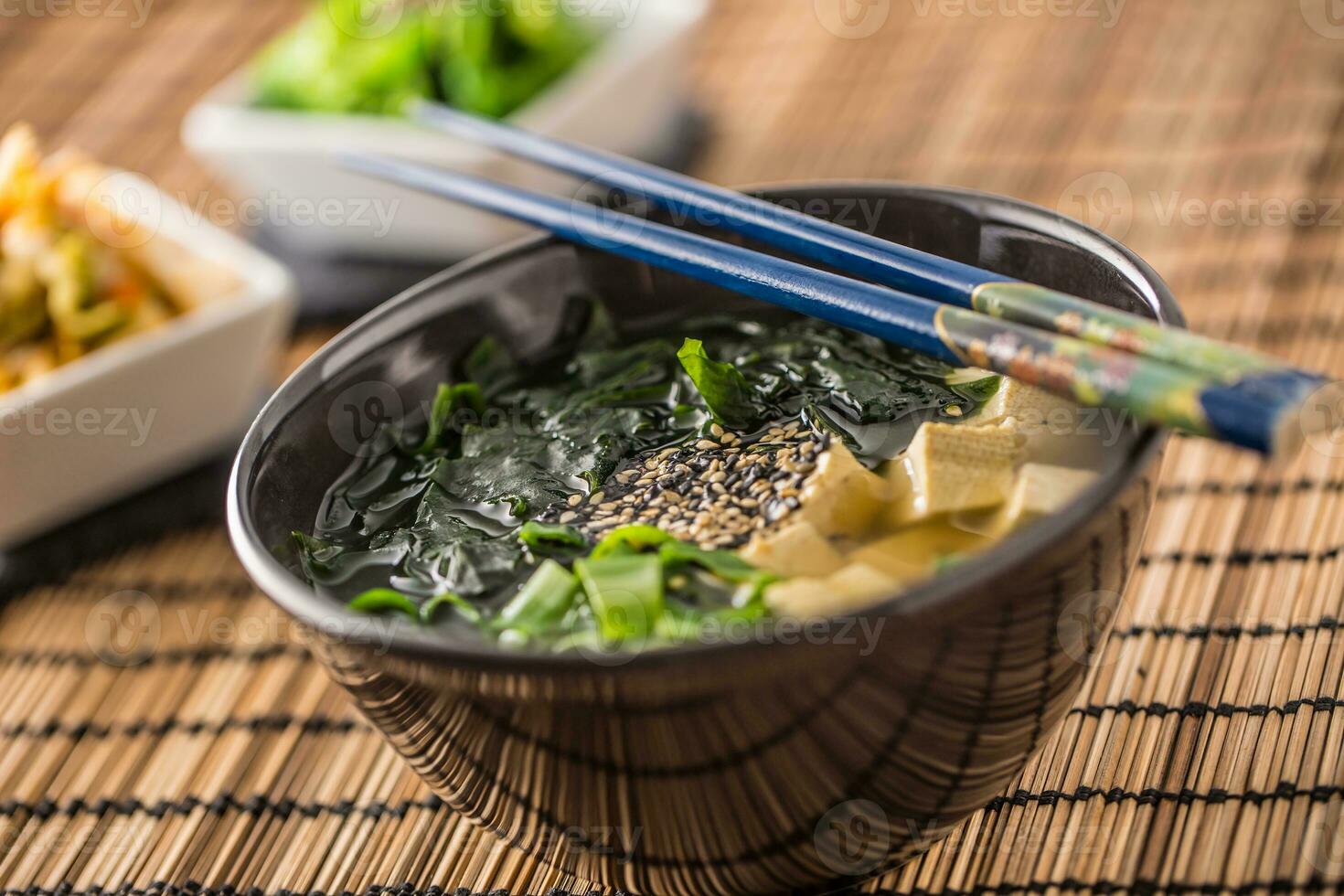 tradicional japonés sopa miso con tofu algas marinas palillos y joven cebolla foto