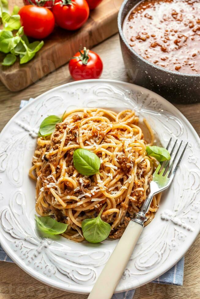 italiano pasta espaguetis boloñesa servido en blanco plato con parmesano queso y albahaca foto