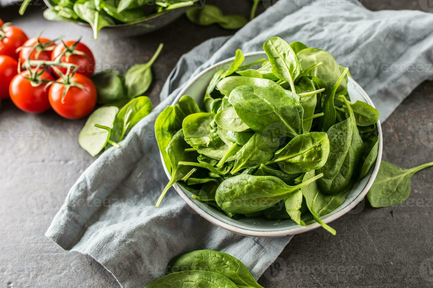 Fresh baby spinach in bowl on dark kitchen table photo