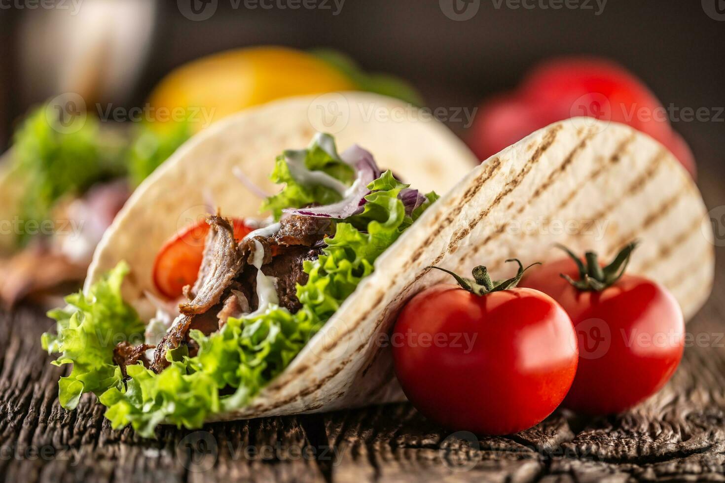 Open meat and veg tortilla on a rustic wooden board photo