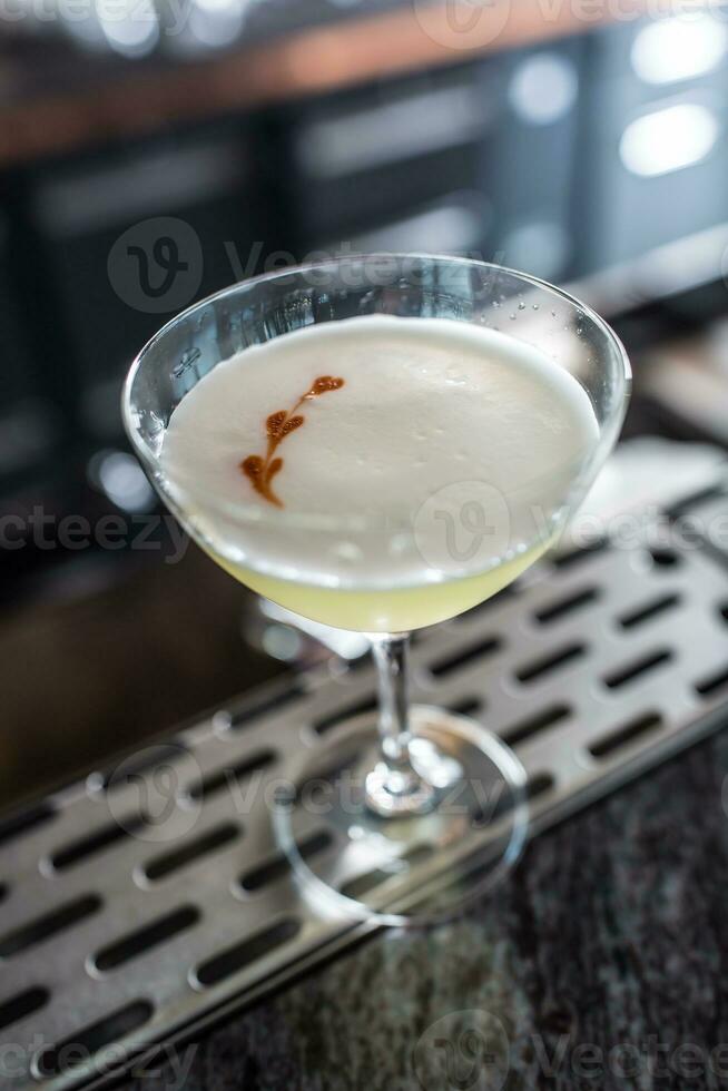 Cocktail drink pisco sour at barcounter in night club or restaurant photo