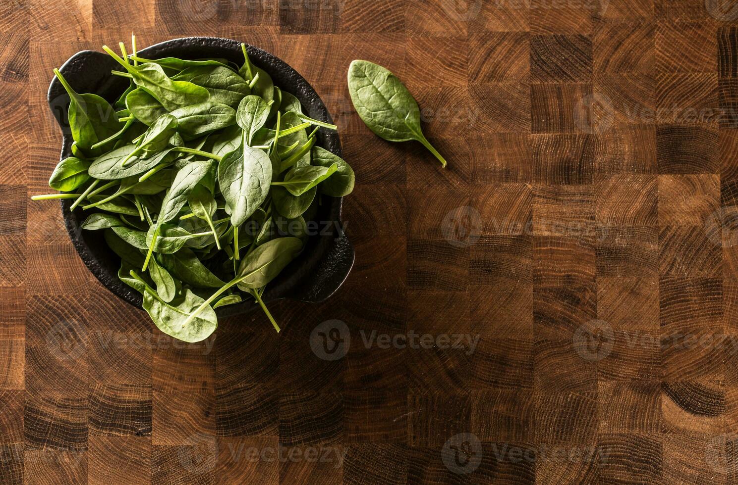 Fresco bebé Espinacas hojas en cuenco en Carnicero tablero foto