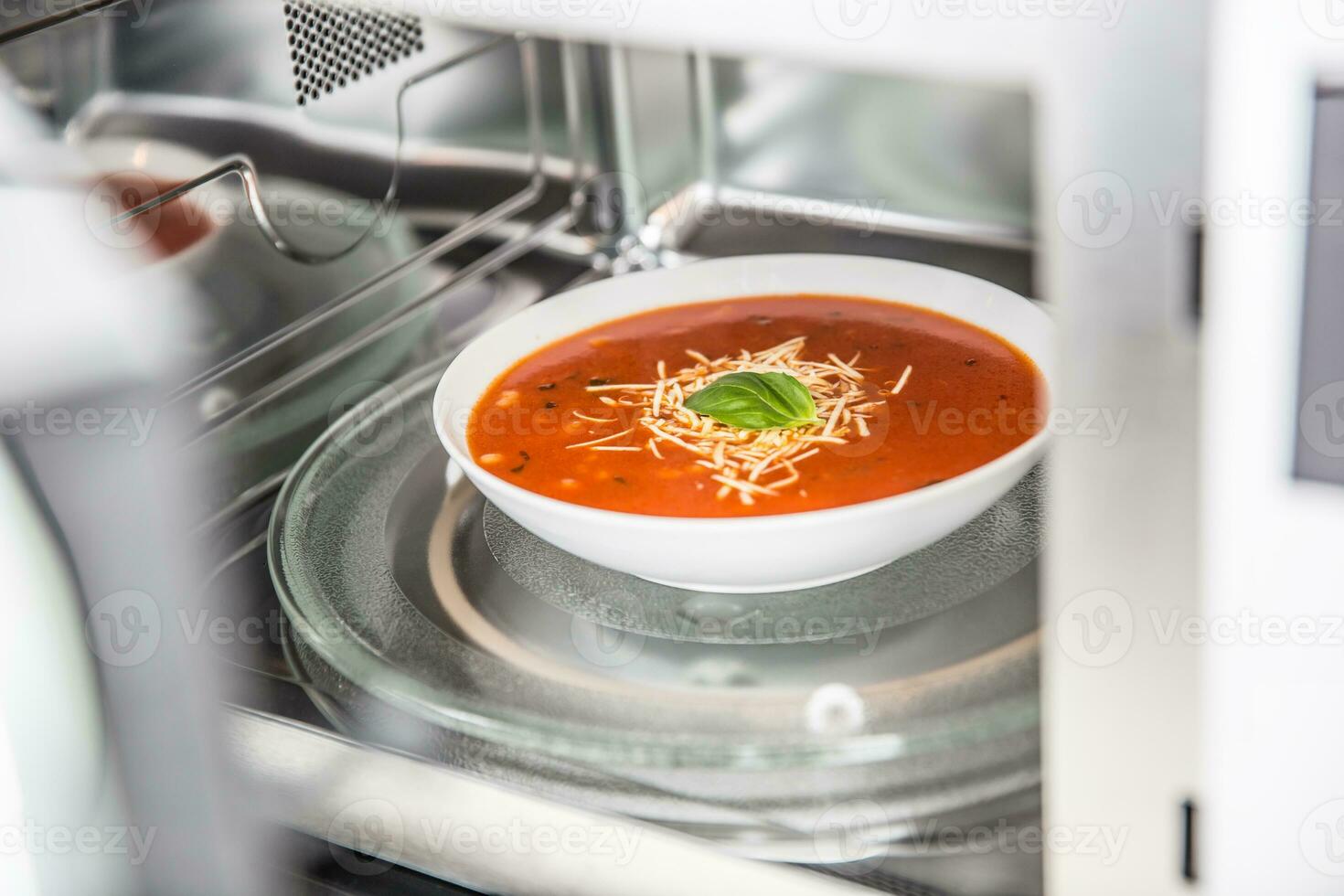 Inside view of new clean staniless microwave oven with a tomato soup in white plate photo