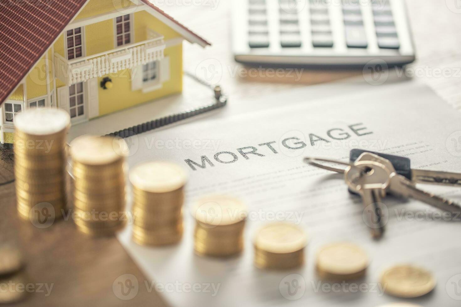 Mortgage contract for the purchase or sale of an apartment house or real estate. Work desk with contract coins model house calculator and pen photo