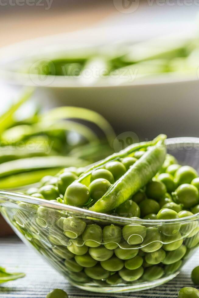 Fresh green pea seeds in bowl on kitchen table photo